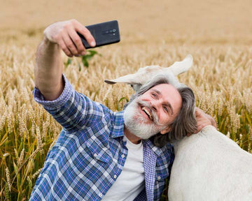 man talking a selfie with a goat in a field