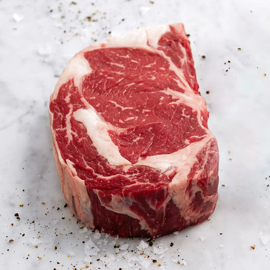 Raw steak on a marble surface with salt and pepper