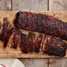 Smoked ribs on a wooden cutting board with a rustic background